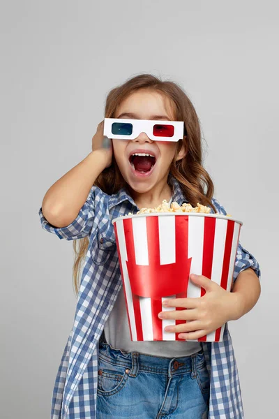 Dziecko dziewczyna w czerwono-niebieskie okulary 3d gospodarstwa wiadro popcorn — Zdjęcie stockowe