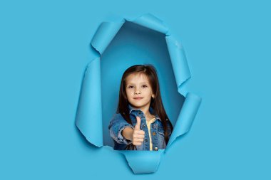 Beyaz tenli küçük kız başparmağını kaldırıyor.