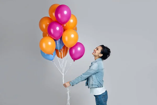 Parlak renkli hava balonlarıyla poz veren kot giyen kız. — Stok fotoğraf