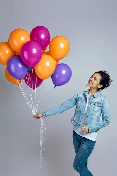 Девушка в джинсе позирует с яркими красочными воздушными шарами — стоковое фото