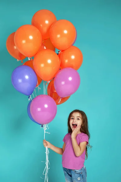 Niña en camiseta rosa posando con globos de aire de colores brillantes —  Fotos de Stock