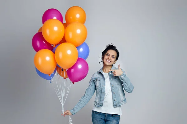 Žena v denimu ukazuje na světlé barevné vzduchové balónky — Stock fotografie