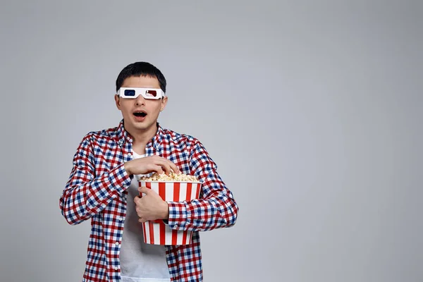 Hombre vistiendo gafas 3d rojo-azul y sosteniendo palomitas de maíz cubo — Foto de Stock