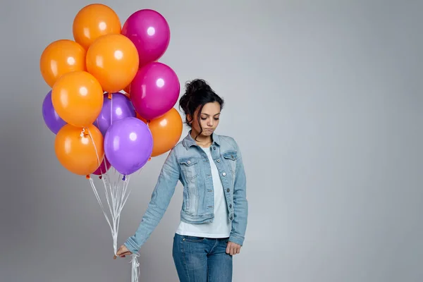 Parlak renkli balonlarla poz veren kot giyen üzgün kız. — Stok fotoğraf