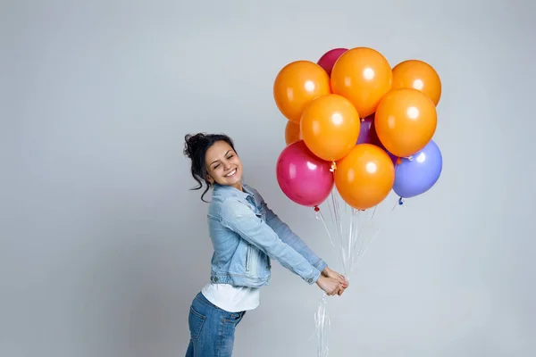 Дівчина в джинсах позує з яскравими барвистими повітряними кулями — стокове фото