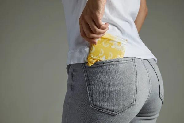 Woman putting sanitary pad into jeans pocket — Stock Photo, Image