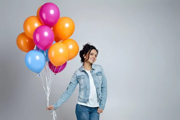 Parlak renkli hava balonlarıyla poz veren kot giyen kız. — Stok fotoğraf