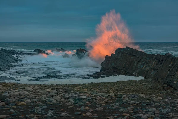 L'onda di colore si sta rompendo sulle pietre — Foto Stock