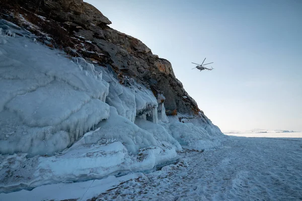 冬季，一架直升机在贝加尔湖着陆 — 图库照片