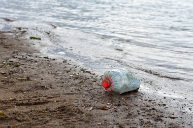 dirty bottle lies on the banks of the river
