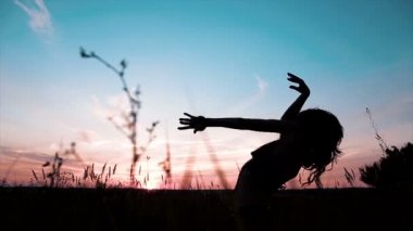 Gün batımı sırasında ince kız dans silüeti.