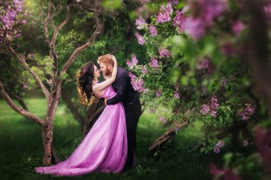 Gelin ve damat leylak ağacının yanında. Birbirine aşık çiftler bahar bahçesinde kucaklaşıyorlar. Boynunda narin bir kolye olan mor kolsuz bir kadın. Siyah takım elbiseli kızıl saçlı adam bir kızı öpüyor ve sarılıyor. Güzel parkta düğün..
