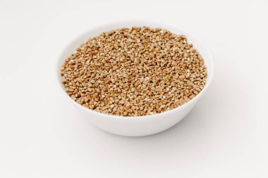 Beyaz izole arkaplanda pişmemiş çiğ karabuğday taneleri.