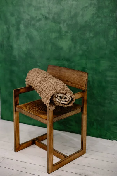 Knitted brown rug lies on an old vintage chair against a green wall. Antique handmade carpet. Isolated home hobby