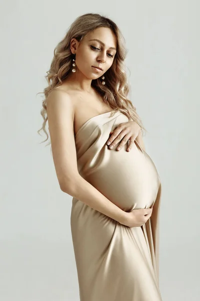 穿着米黄色缎子衣服的漂亮孕妇摸着她的大肚子 靠近点母亲 人和期望的概念 怀孕的女孩怀孕了被隔离了 — 图库照片