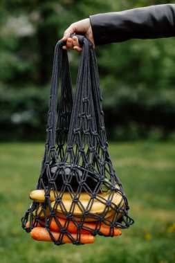 Meyveli ağ torbası, kadın elinde sebze. Tarz sahibi genç bir kadının eli. İpli ağ alışveriş çantası. Modern yeniden kullanılabilir alışveriş, eko yaşam tarzı, sıfır atık konsepti. Sağlıklı, organik, temiz yemek..