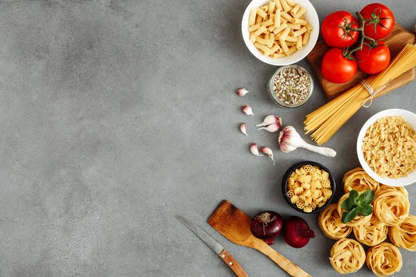 Ahşap masa üzerinde makarna pişirmek için malzemeli spagetti ve fettuccine ile ahşap mutfak tahtası boş, üst manzara. Kırsal tarzda. Boş alan ile düz uzandı