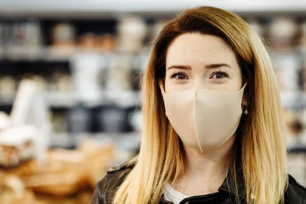 Bir salgın sırasında süpermarketten alışveriş yapan koruyucu tıbbi maskeli güzel bir kadının portresi. Alıcı bakkaldan alışveriş yapar..