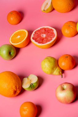 greyfurt, portakal, elma, armut pembe arka planda yatar