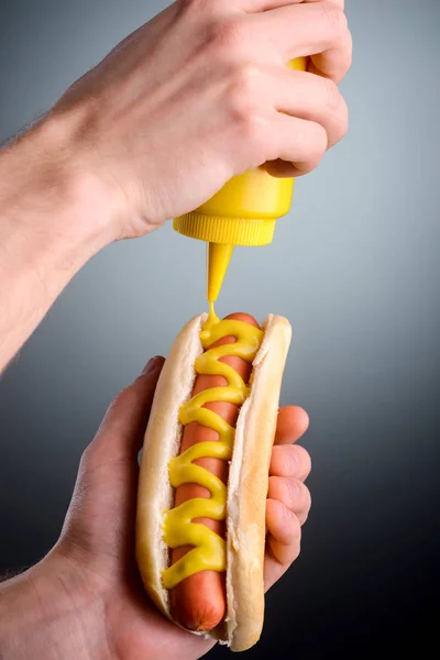 Squeezing mustard on grey background — Stock Photo, Image