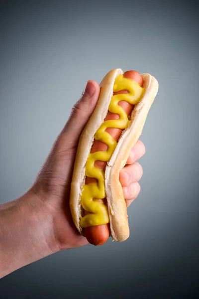 Mão masculina segurando cachorro quente — Fotografia de Stock