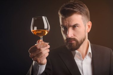 Adam alkol içki tadımı. Seçici odak bir bardak konyak. Bir cam holding ve içecek görünümünü değerlendirerek sommelier.