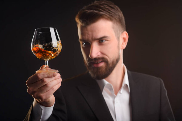 A glass of brandy in focus. Splashes of an orange swirled alcohol beverage after sommelier shaked the glass. Degustation process captured in studio shot.