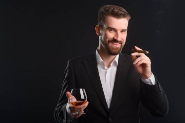 Maço bir pahalı puro sigara. Biraz gülmek bir bardak konyak ve Küba purosu her iki elinde tutuyor. Ufuk duman akışının ile koyu arka plan.