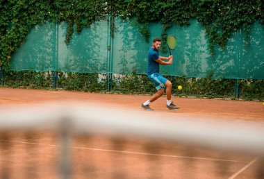 Tenisçi topu kaçırıyor. Açık sahada antrenman yaparken formda genç bir adam..