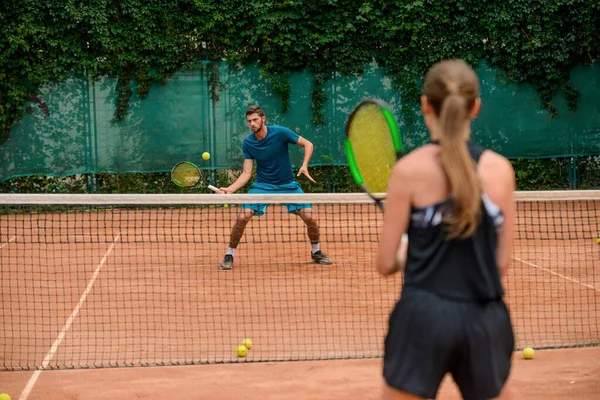 Oung couple playing tennis at outdoor court — Stock Photo, Image