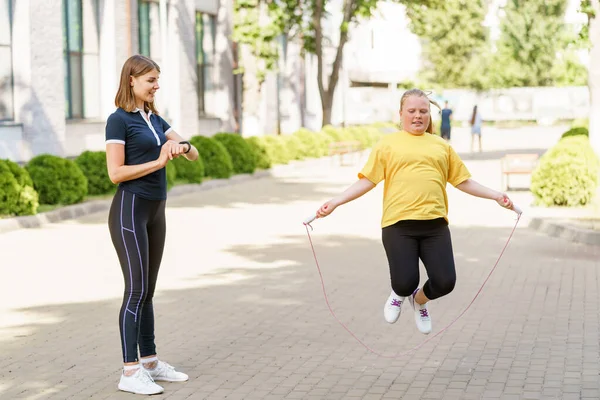 Girl jumping with a rope, doing cardio workout under her fitness trainers control