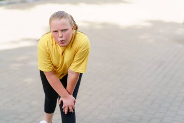 Yorgun kız eğildi ve yorucu egzersizden sonra soluk alıyor..