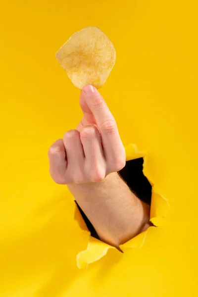Lanche saboroso e crocante, propaganda de alimentos através de um buraco rasgado em amarelo — Fotografia de Stock