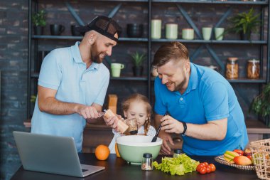 Babalar ve kızları salata pişiriyor.