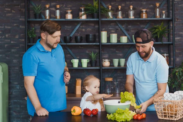 Οι γκέι γονείς και το παιδί τους μαγειρεύουν μια σαλάτα μαζί. — Φωτογραφία Αρχείου