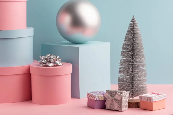 Drzewo jodłowe, piłka, okrągłe i kwadratowe pudełka na różowym i ciemnym tle — Zdjęcie stockowe
