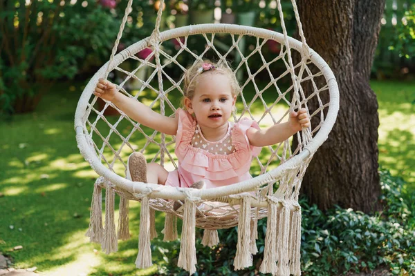 Schönes kleines Mädchen auf einem Gitterhängemattenstuhl — Stockfoto