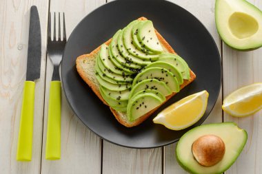 Avokado ve limonlu tost, susam tohumları serpiştirilmiş.