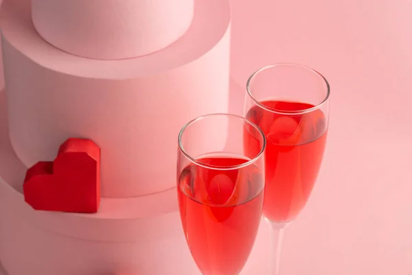 Close-up on two glasses of red sparkling wine and heart on pink background — Stock Photo, Image