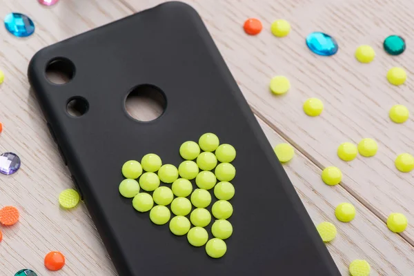 Black phone case decorated with yellow bead heart — Stock Photo, Image