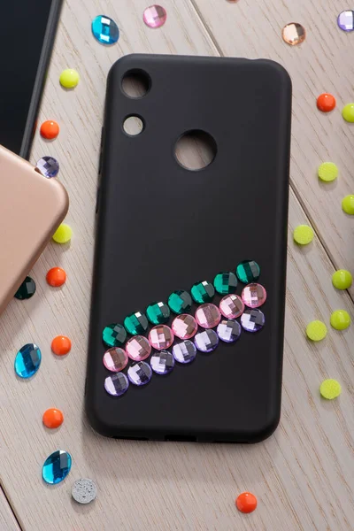 Black phone case decorated with colorful rhinestone stripes — Stock Photo, Image