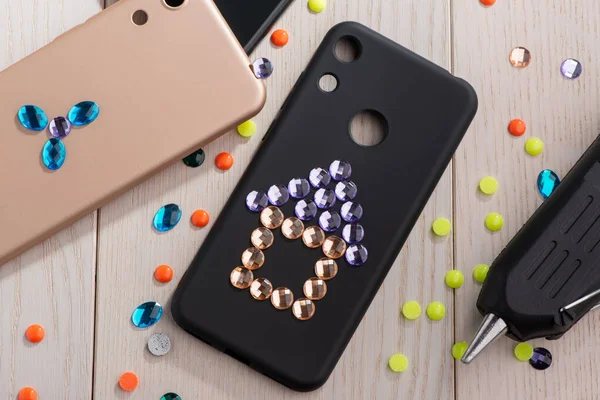 Child attaching rhinestones onto phone cases with a glue gun — Stock Photo, Image