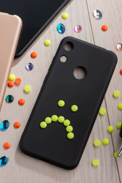 Black phone case decorated with yellow sad smile — Stock Photo, Image