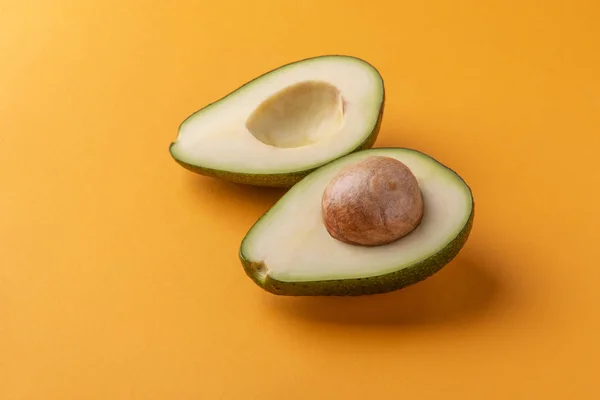 Avocado μισά με πυρήνα σε πορτοκαλί φόντο — Φωτογραφία Αρχείου