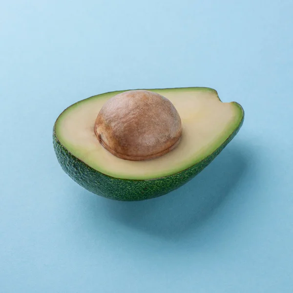 Avocado μισό με πυρήνα σε μπλε φόντο — Φωτογραφία Αρχείου