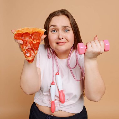 Kadın pizza ve egzersiz arasında seçim yapıyor. Abur cuburdan kurtuluyorum.