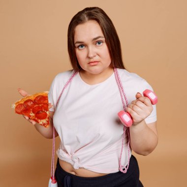 Bej arka planda pizza ve halterli kadın.