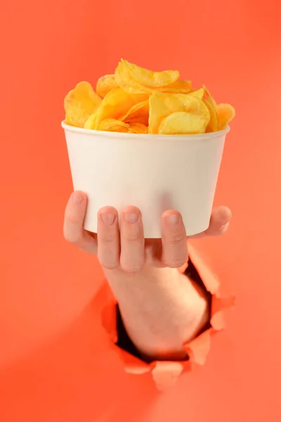 Mão segurando uma xícara inteira de batatas fritas — Fotografia de Stock