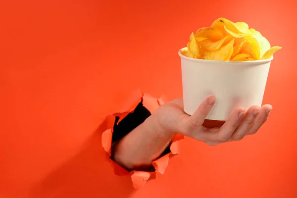 Mão segurando uma xícara de batatas fritas — Fotografia de Stock