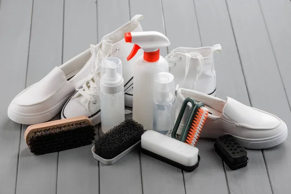 Varios zapatos blancos y suministros de cuidado para ellos en la mesa de madera — Foto de Stock